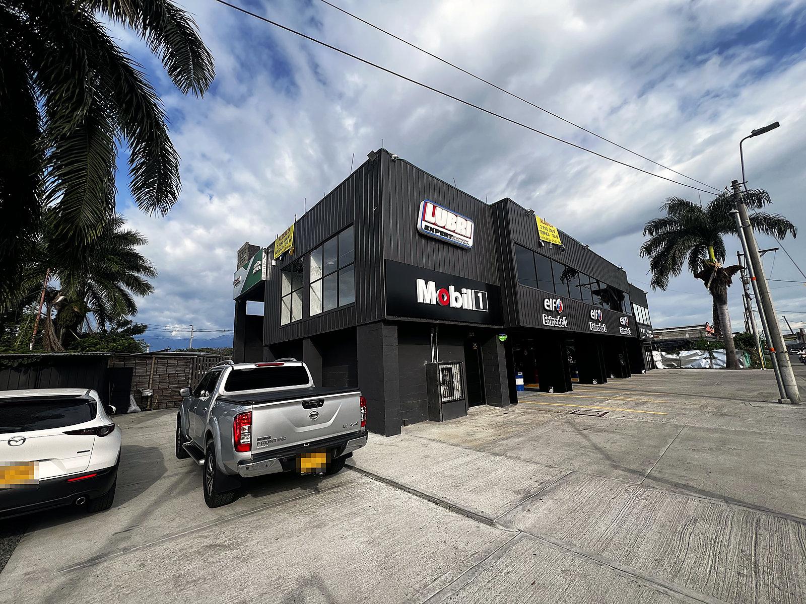 Fachada terminada de edificio comercial en Palmira con revestimiento oscuro y ventanales