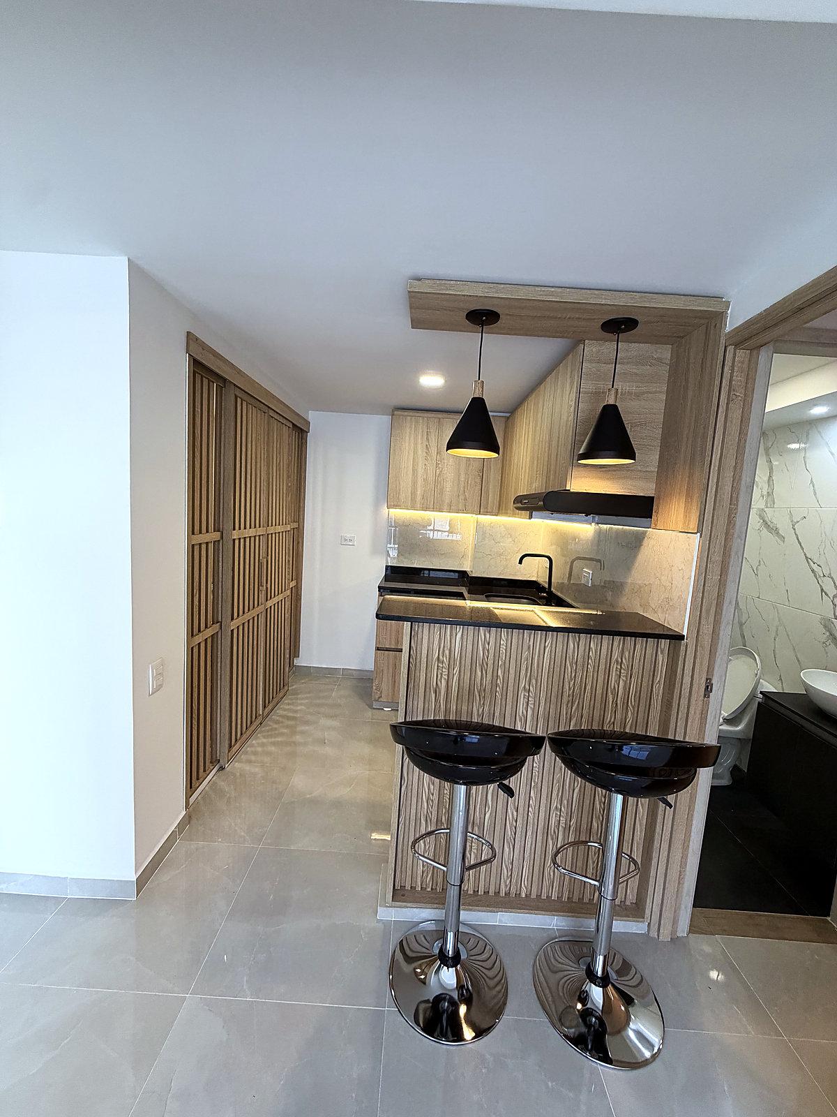 Cocina integral con barra y paneles de madera en un apartamento terminado